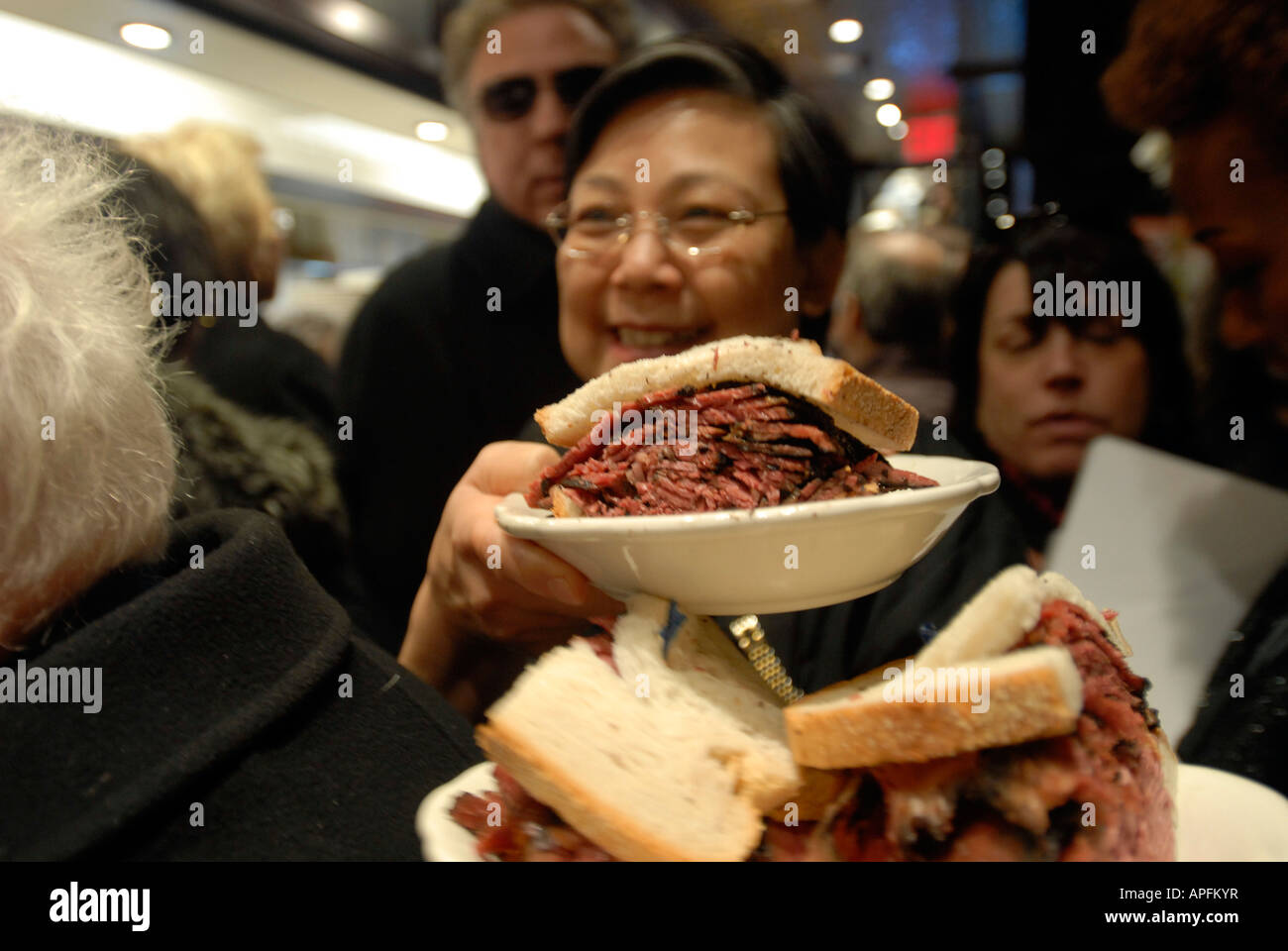 Waitperson offre un sandwich pastrami attraverso le affollate 2nd Avenue Deli Foto Stock