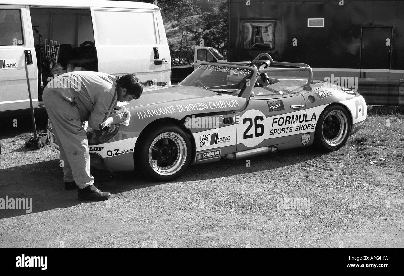 Uomo al lavoro su corse di auto sportive nel box a Cadwell Park. Foto Stock