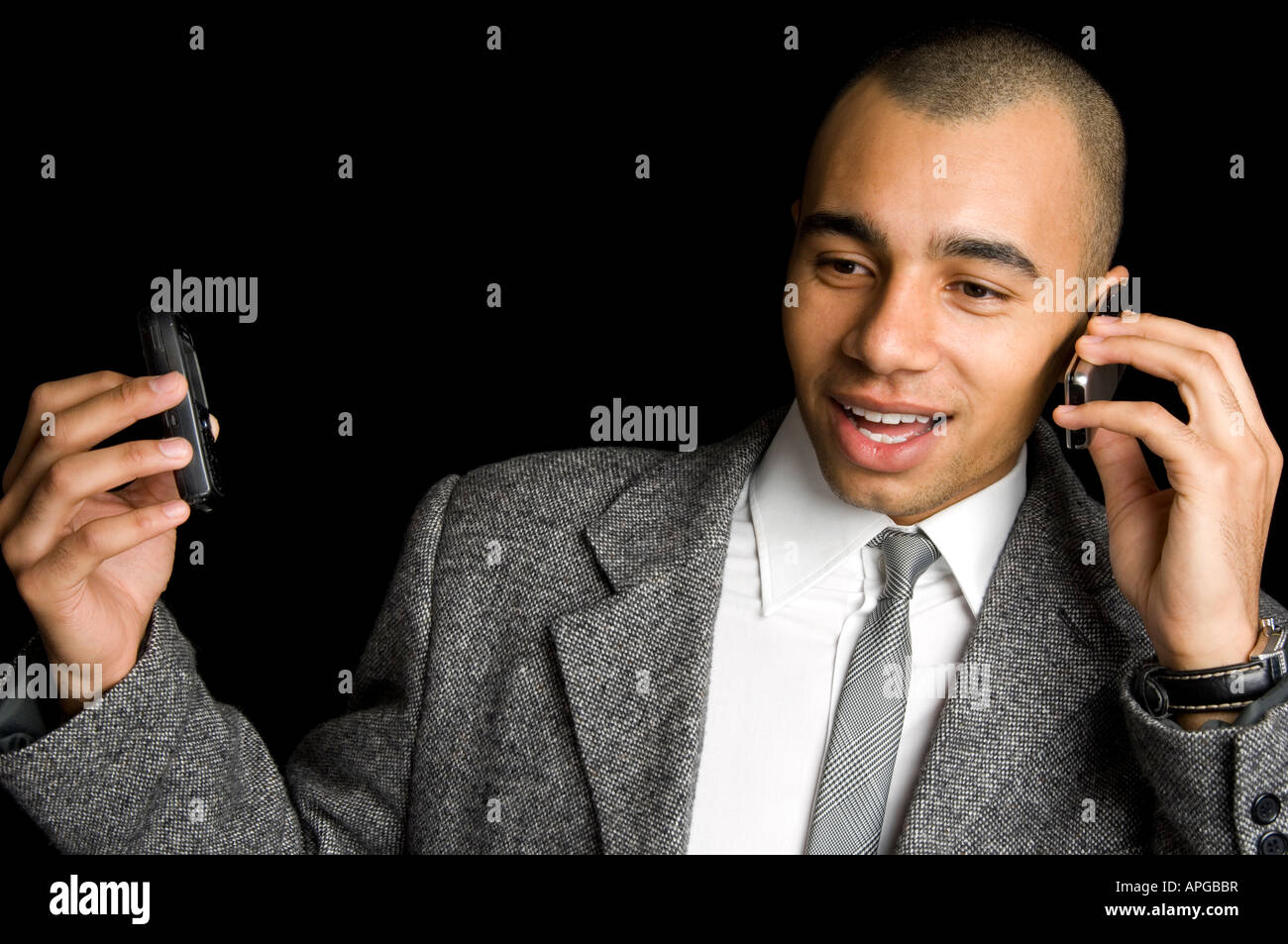 Giovani razza mista imprenditore chattare su due telefoni cellulari Foto Stock