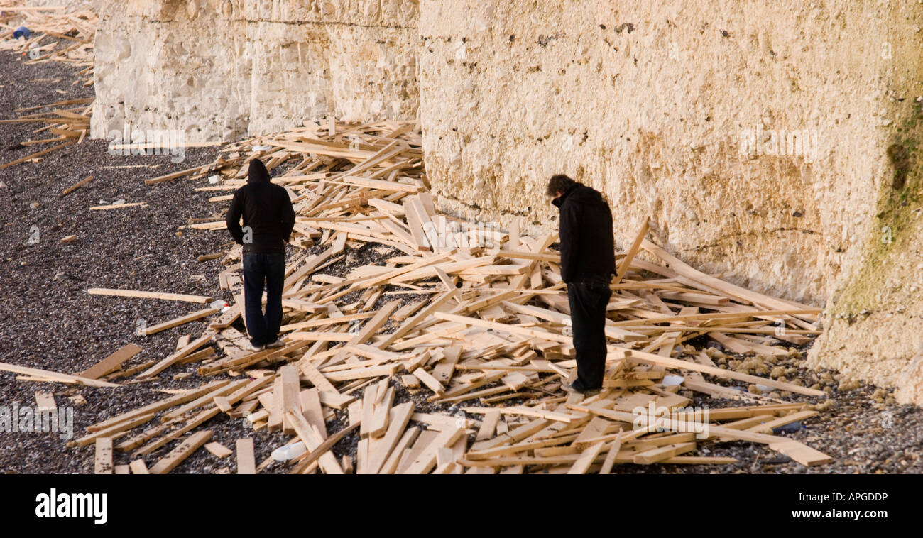 Due uomini a piedi tra il legname segato cargo lavato fino a Sussex spiagge a seguito del naufragio del principe di ghiaccio. Foto Stock