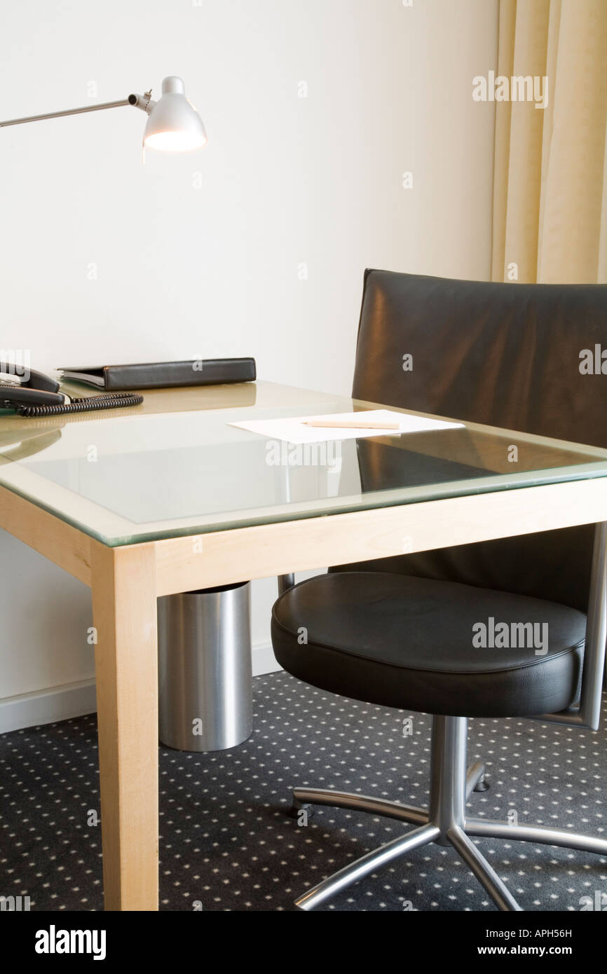 Scrivania con lampada e cuoio nero sedia girevole. Potrebbe descrivere una scrivania in ufficio, home studio o camera di albergo. Foto Stock