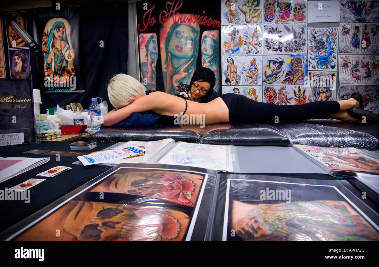 Alla prima relazione annuale di Brighton Tattoo Convention Tattoo Artist Jo Harrison lavora su un client circondato dalla sua tecnica flash Foto Stock