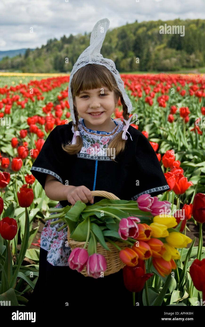 Giovani sorridente ragazza olandese con un cesto pieno di tulipani Foto Stock