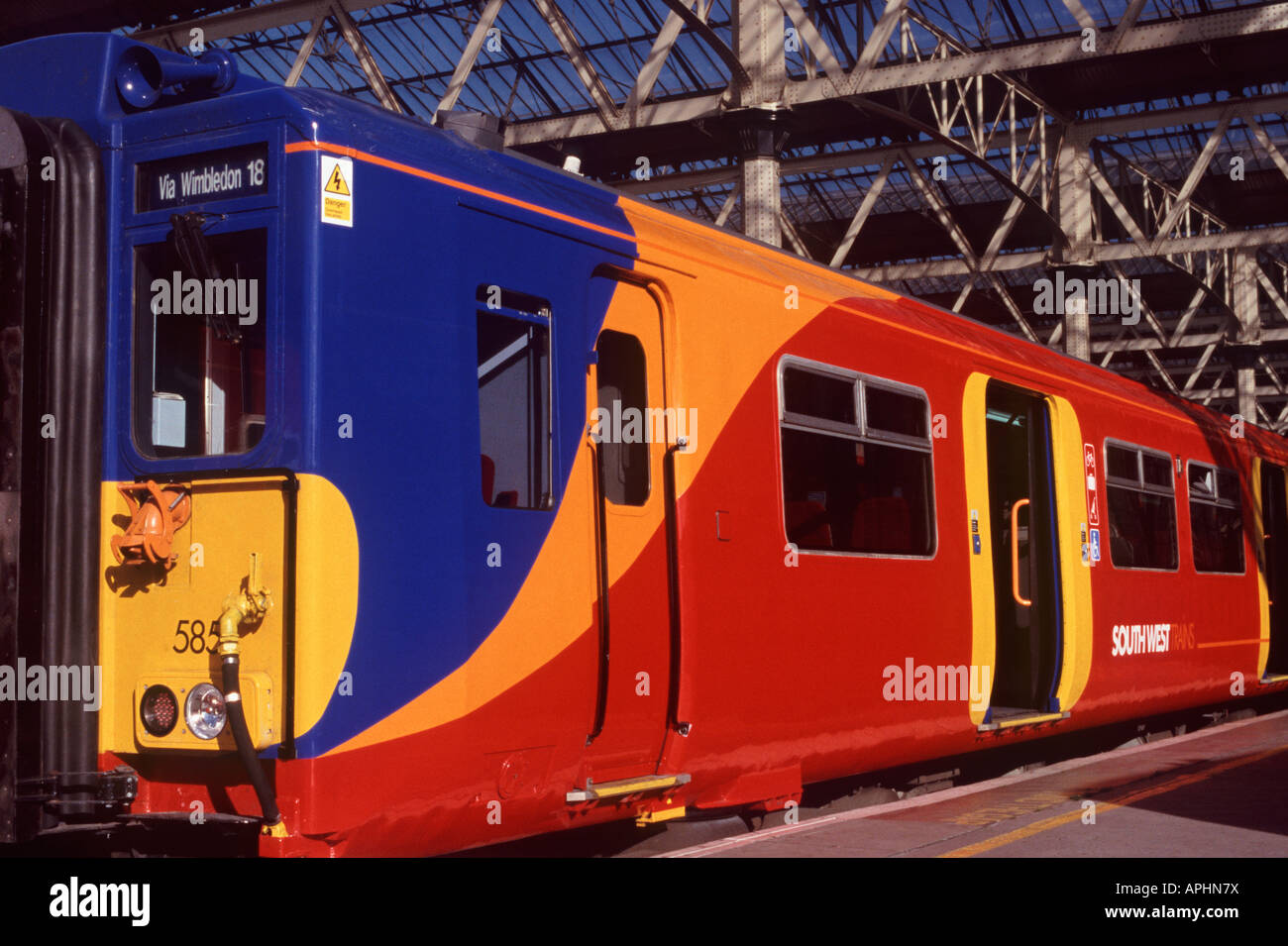 Elettrico treno dei pendolari motore e carrello che mostra colore rosso brillante, giallo arancio e blu della livrea e alta visibilità marcature della porta Foto Stock