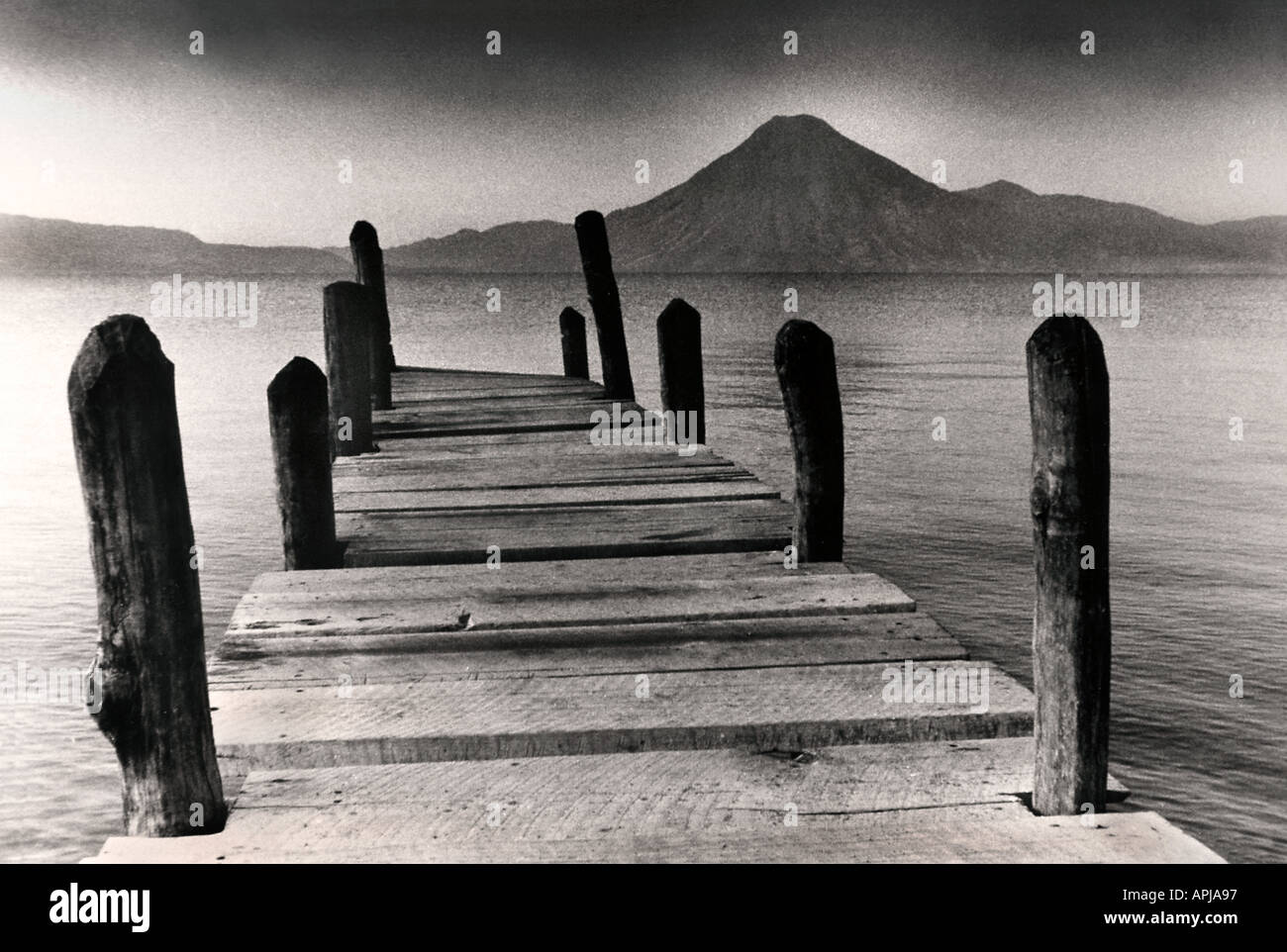 Colpo mistico di pontili in legno a Panajachel lago Atitlan all'alba Guatemala vista su San Pedro vulcano dai toni seppia Foto Stock