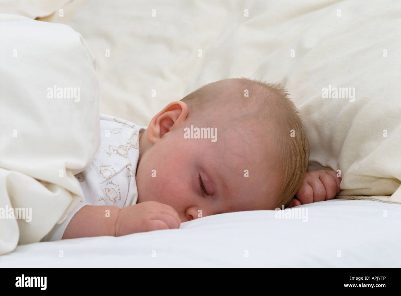 Cinque mesi il bambino addormentato con il lato stampato rivolto verso il basso nel letto Foto Stock