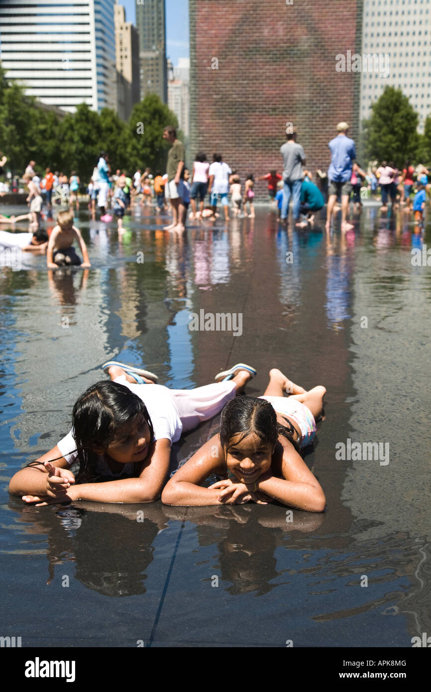 ILLINOIS Chicago due ragazze sdraiato in acqua poco profonda giocare i bambini intorno a corona Fontana nel Millennium Park Foto Stock