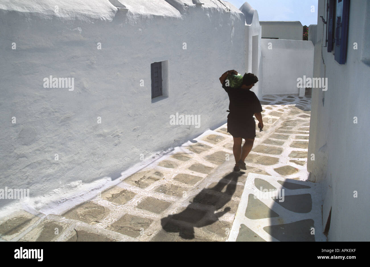 Uomo che cammina verso il basso strada stretta viuzza, Mykonos Grecia Foto Stock