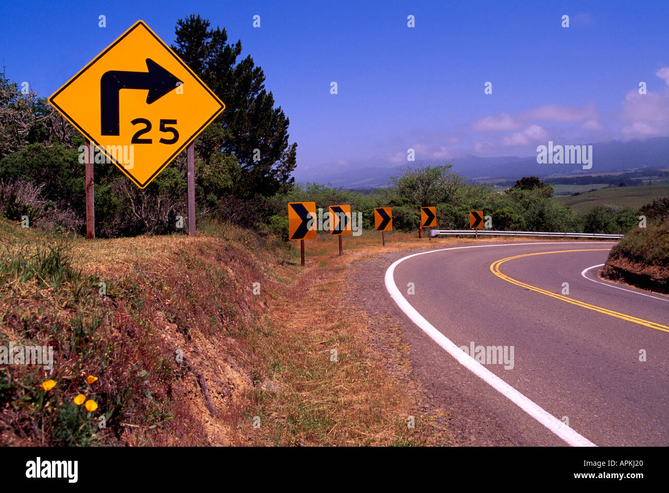 Il limite massimo di velocità su strada di avvertimento di segno i conducenti di Sharp curva a destra lungo la Pacific Coast Highway 1, CALIFORNIA, STATI UNITI D'AMERICA Foto Stock