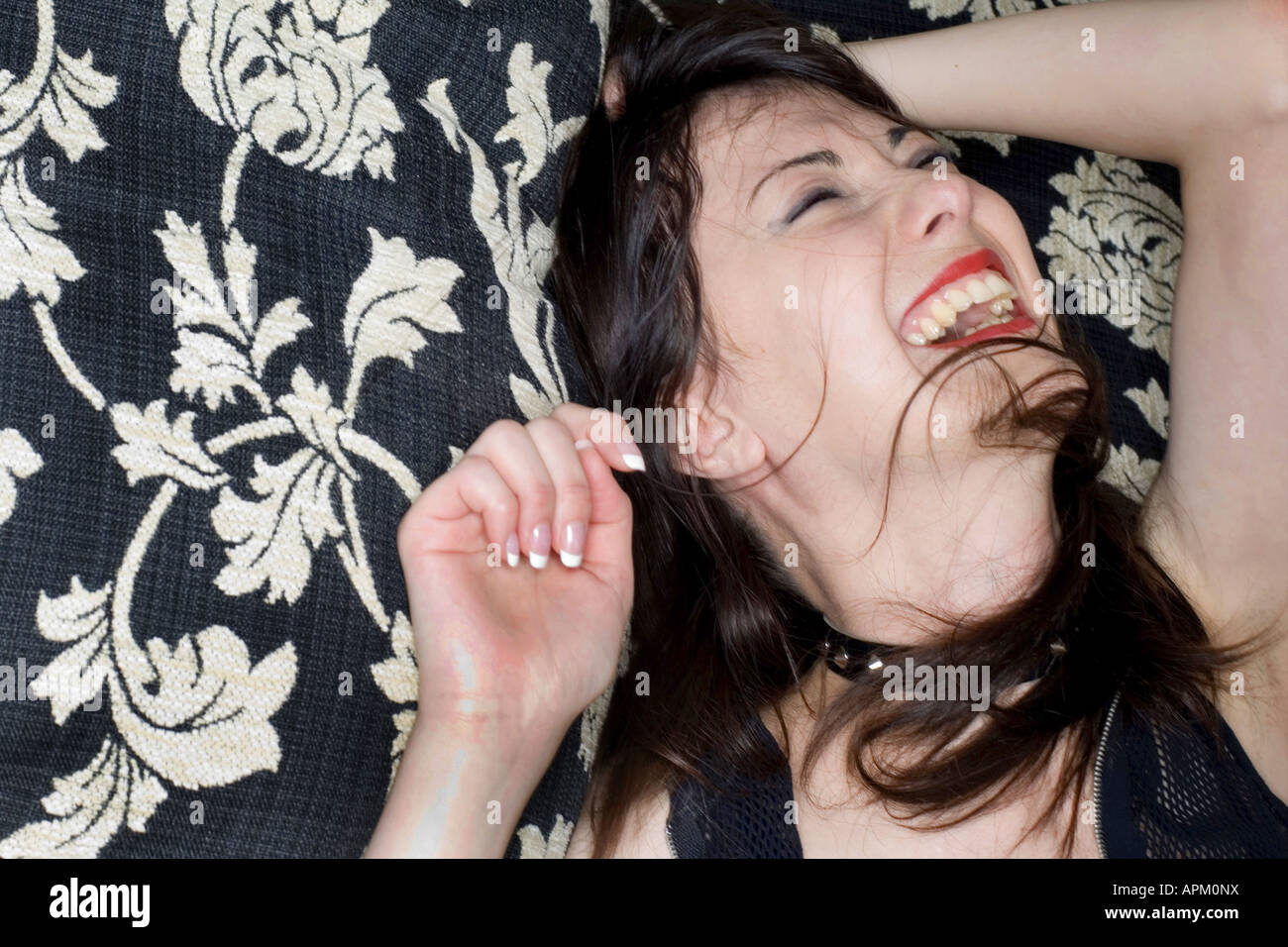 Giovane donna sdraiata su un letto, ridendo Foto Stock