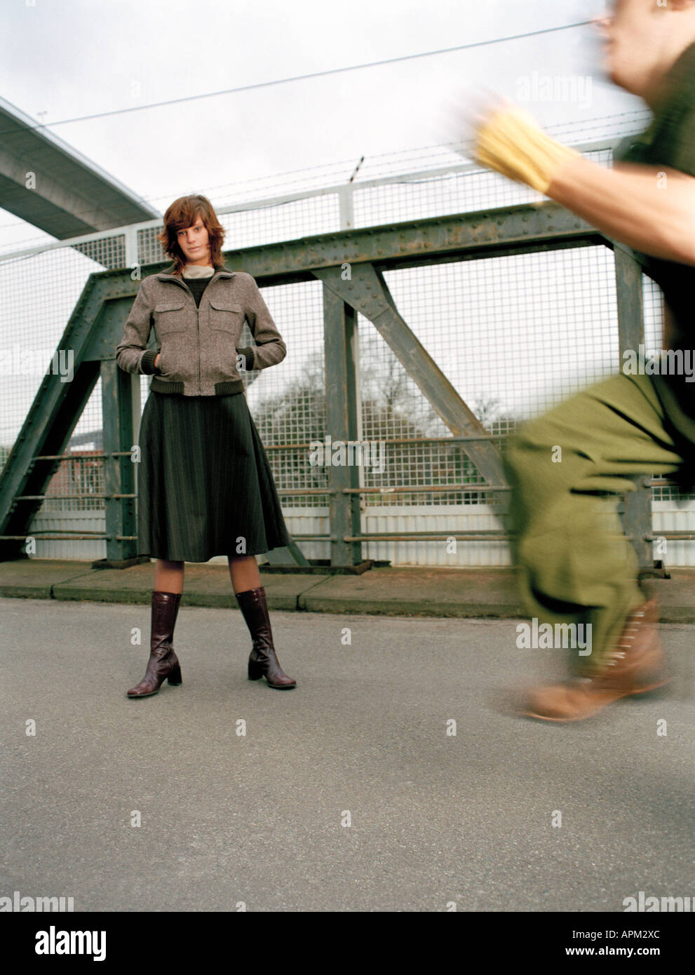 Donna in piedi sul ponte, l'uomo in esecuzione Foto Stock