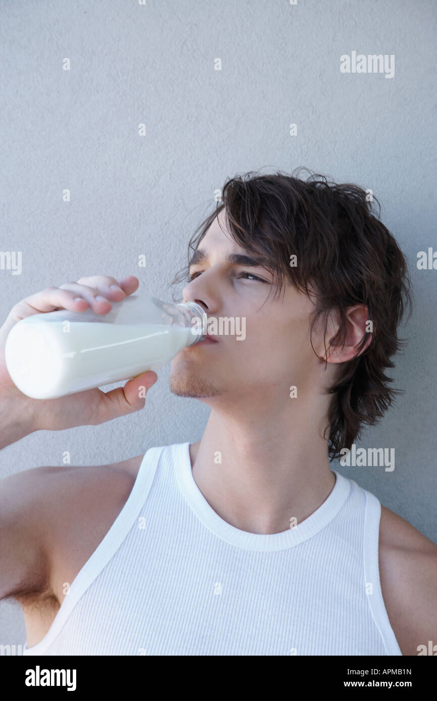Giovane uomo di bere latte dalla bottiglia di latte Foto Stock