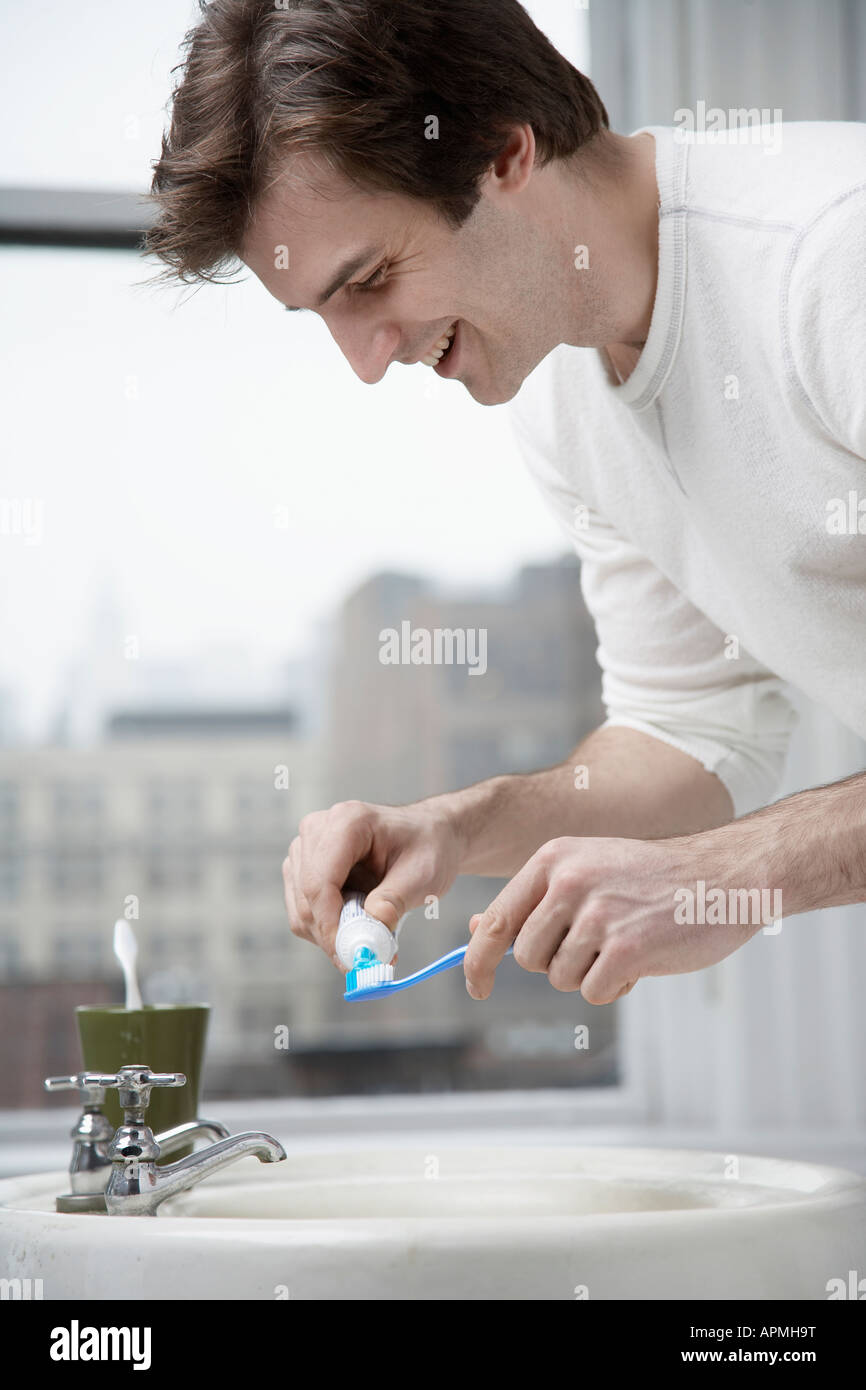 Giovane uomo spremitura di dentifricio all'esterno del tubo Foto Stock