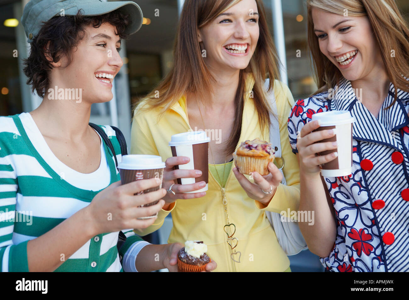 Tre ragazze adolescenti bere take-out di caffè e mangiare torte Foto Stock