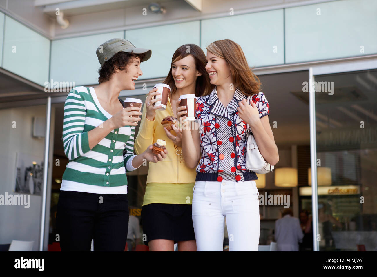 Tre ragazze adolescenti bere take-out di caffè e mangiare torte Foto Stock