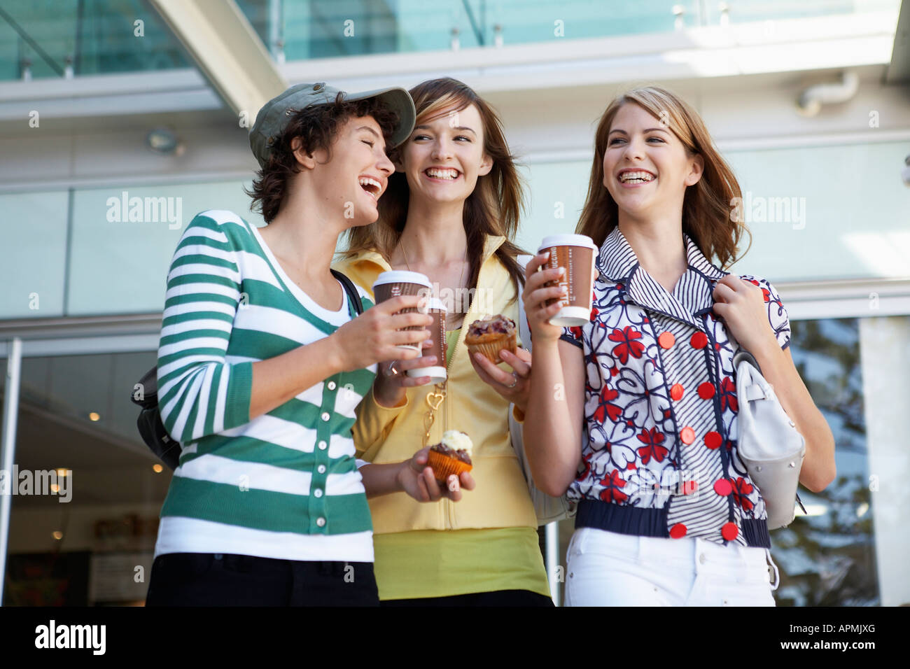Tre ragazze adolescenti bere take-out di caffè e mangiare dolci (basso angolo di visualizzazione) Foto Stock