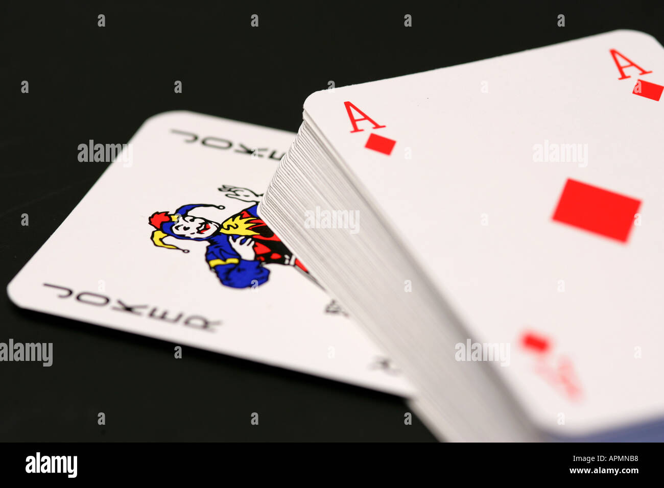 Mazzo di carte da gioco con red asso di cuori sulla parte superiore e i colorati Joker card spuntavano, concettuale su sfondo nero Foto Stock