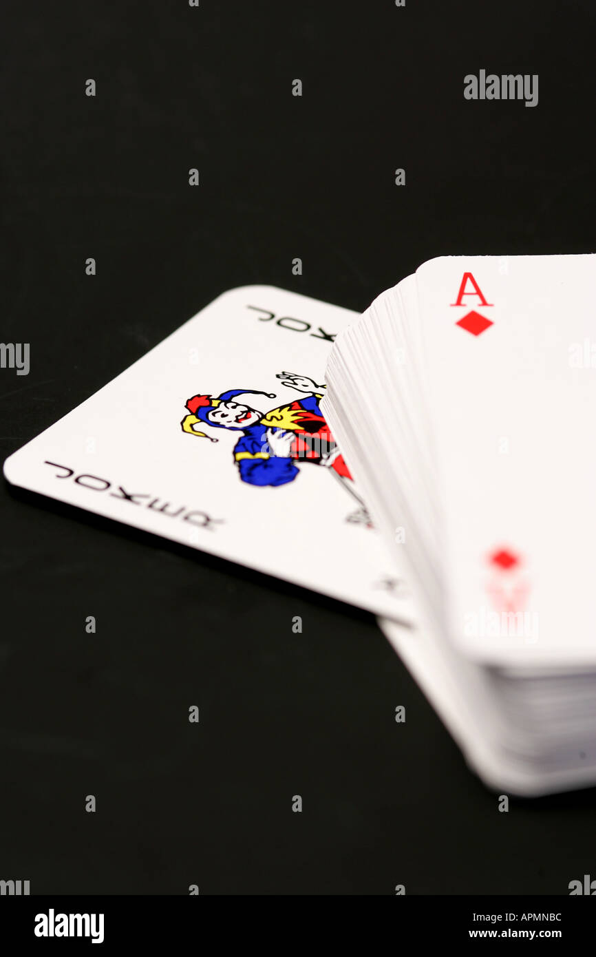 Mazzo di carte da gioco con red asso di cuori sulla parte superiore e i colorati Joker card spuntavano, concettuale su sfondo nero Foto Stock