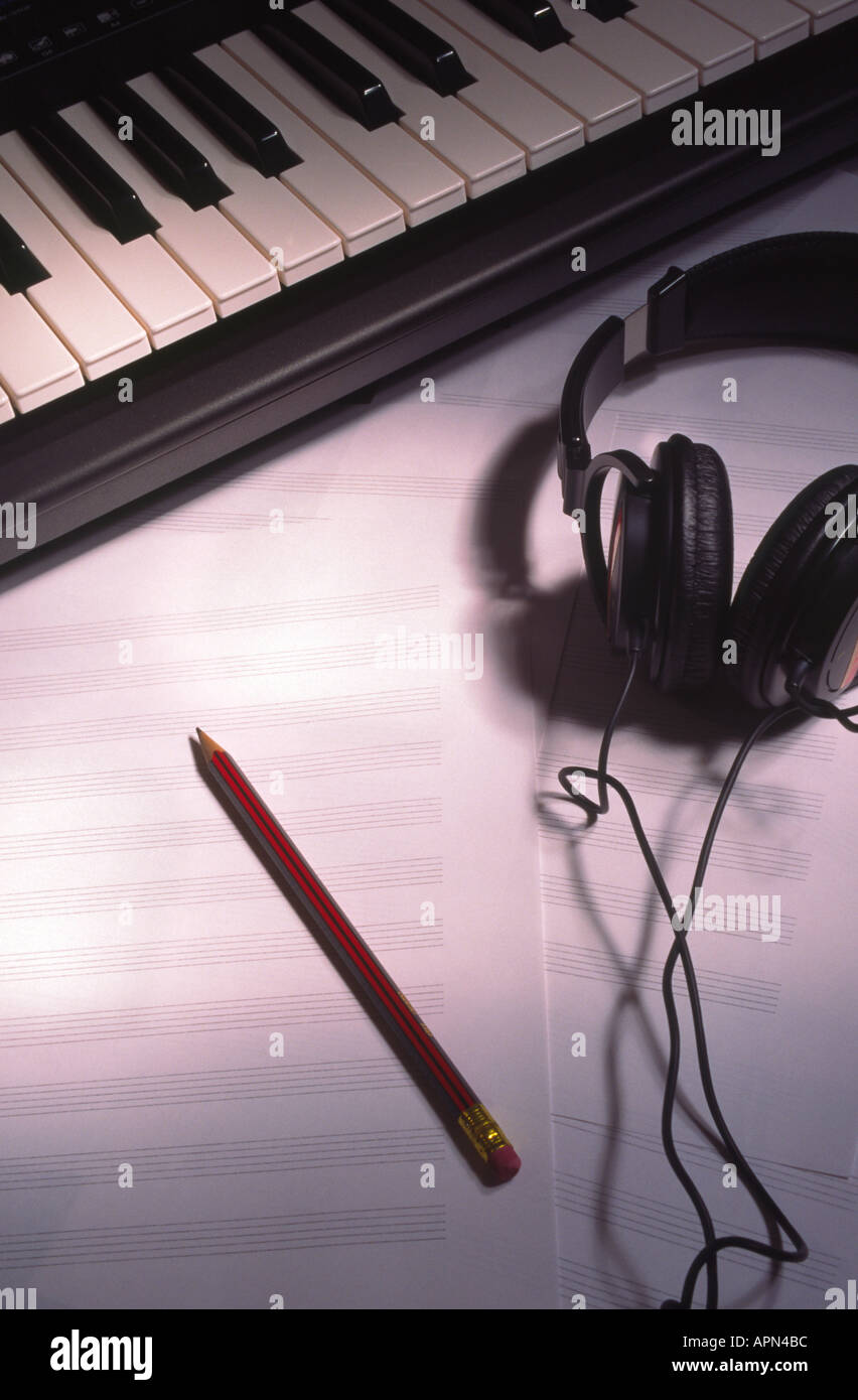 La scrittura di musica tastiera cuffie e i fogli bianchi di carta da musica con matita Foto Stock