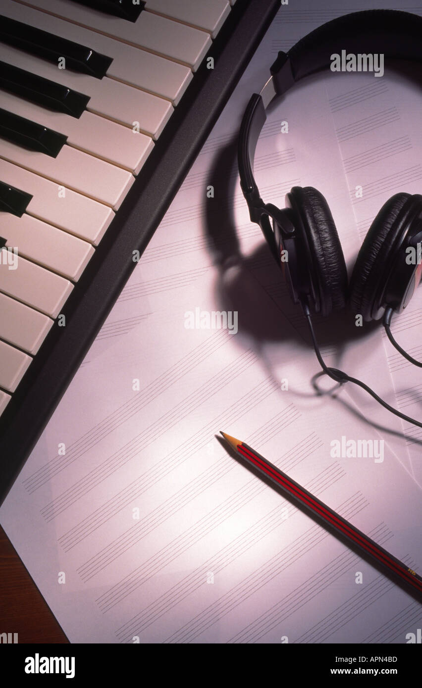 La scrittura di musica tastiera cuffie e i fogli bianchi di carta da musica con matita Foto Stock