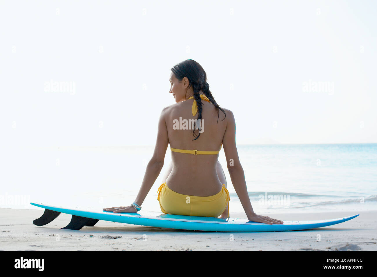 Giovane donna seduta sulla tavola da surf, San Giovanni, Isole Vergini americane, STATI UNITI D'AMERICA Foto Stock