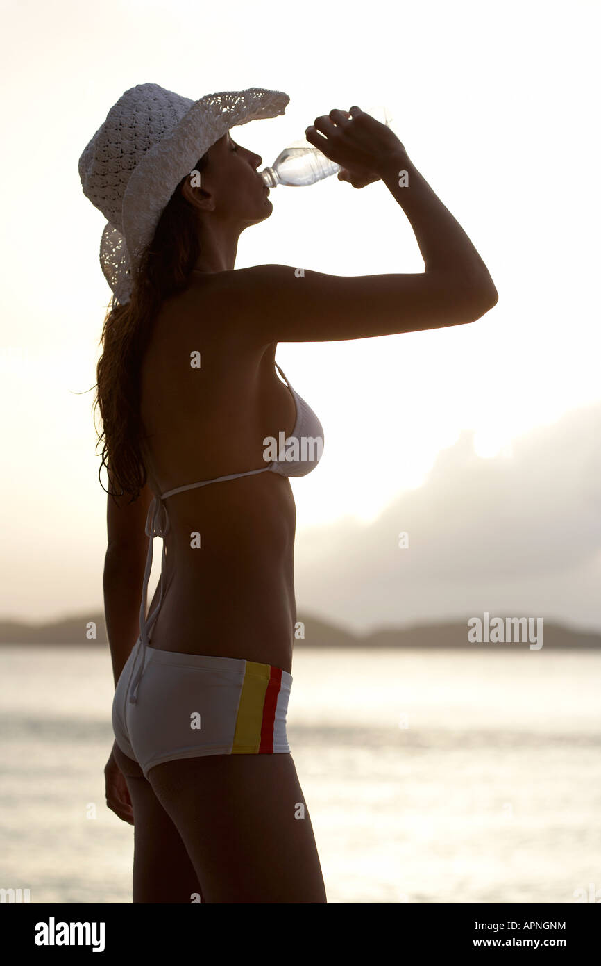 Giovane donna acqua potabile sulla spiaggia, San Giovanni, Isole Vergini americane, STATI UNITI D'AMERICA Foto Stock