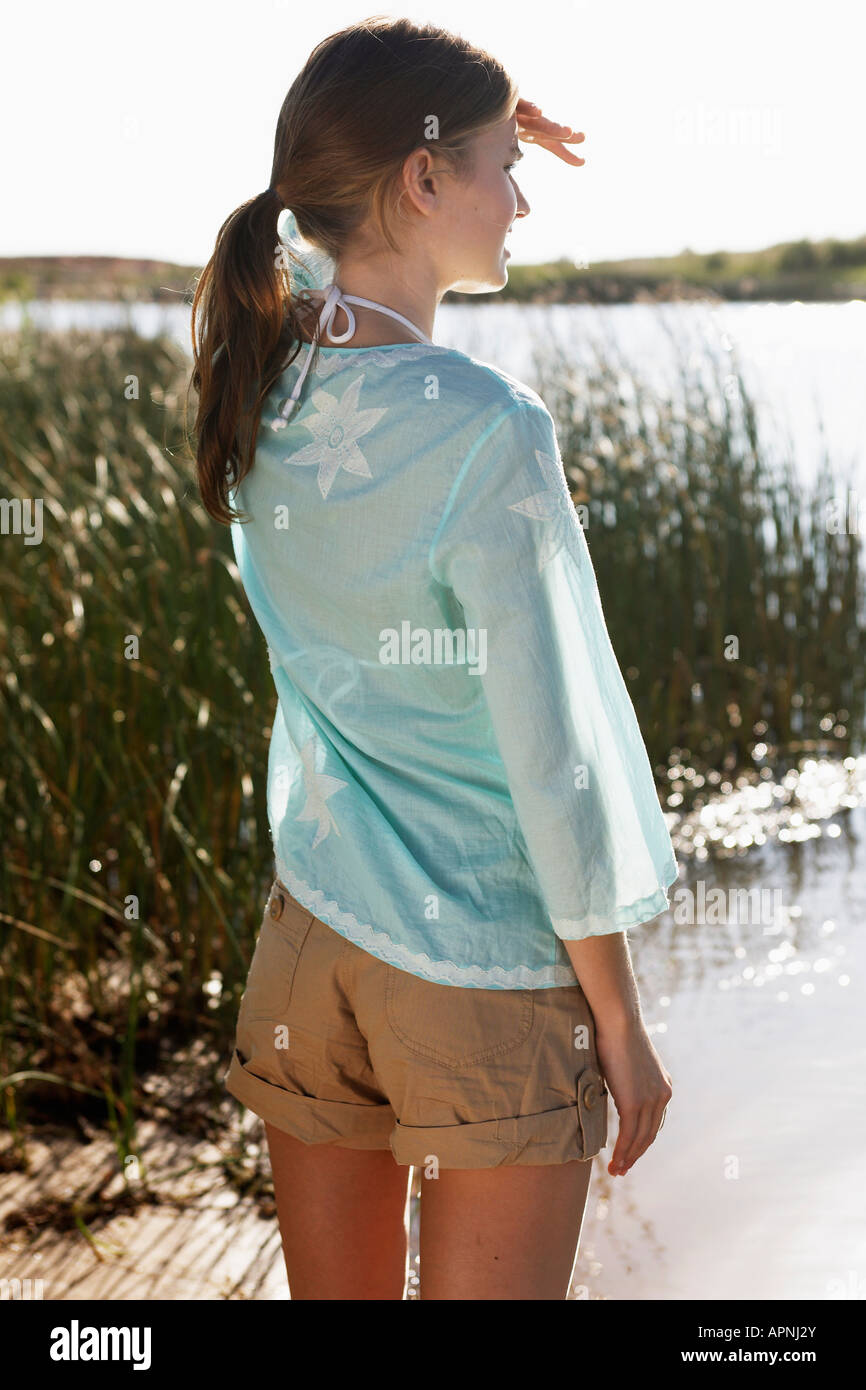 Giovane donna schermare gli occhi e guardando il lago Foto Stock