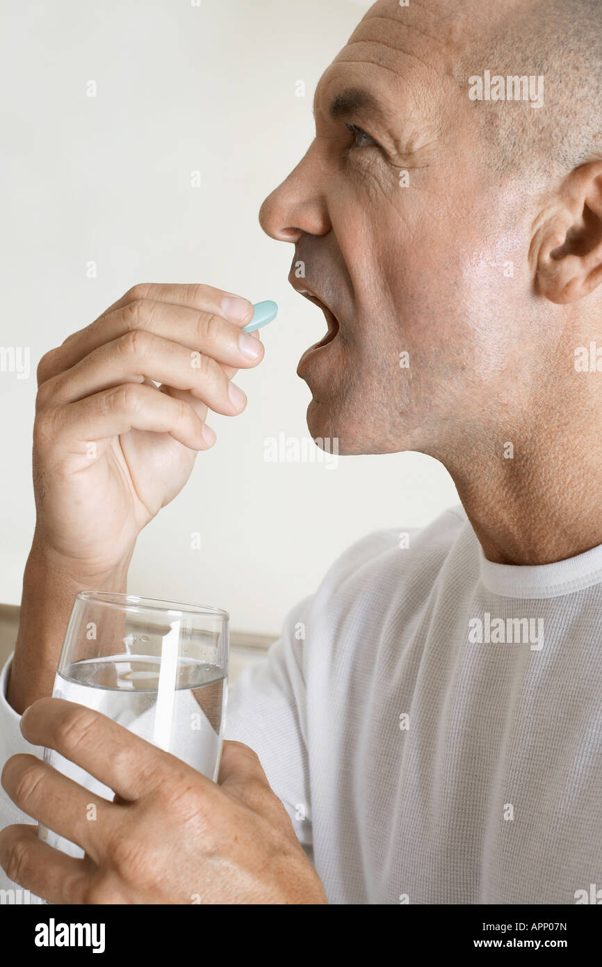 Uomo maturo avente una pillola di vitamine Foto Stock