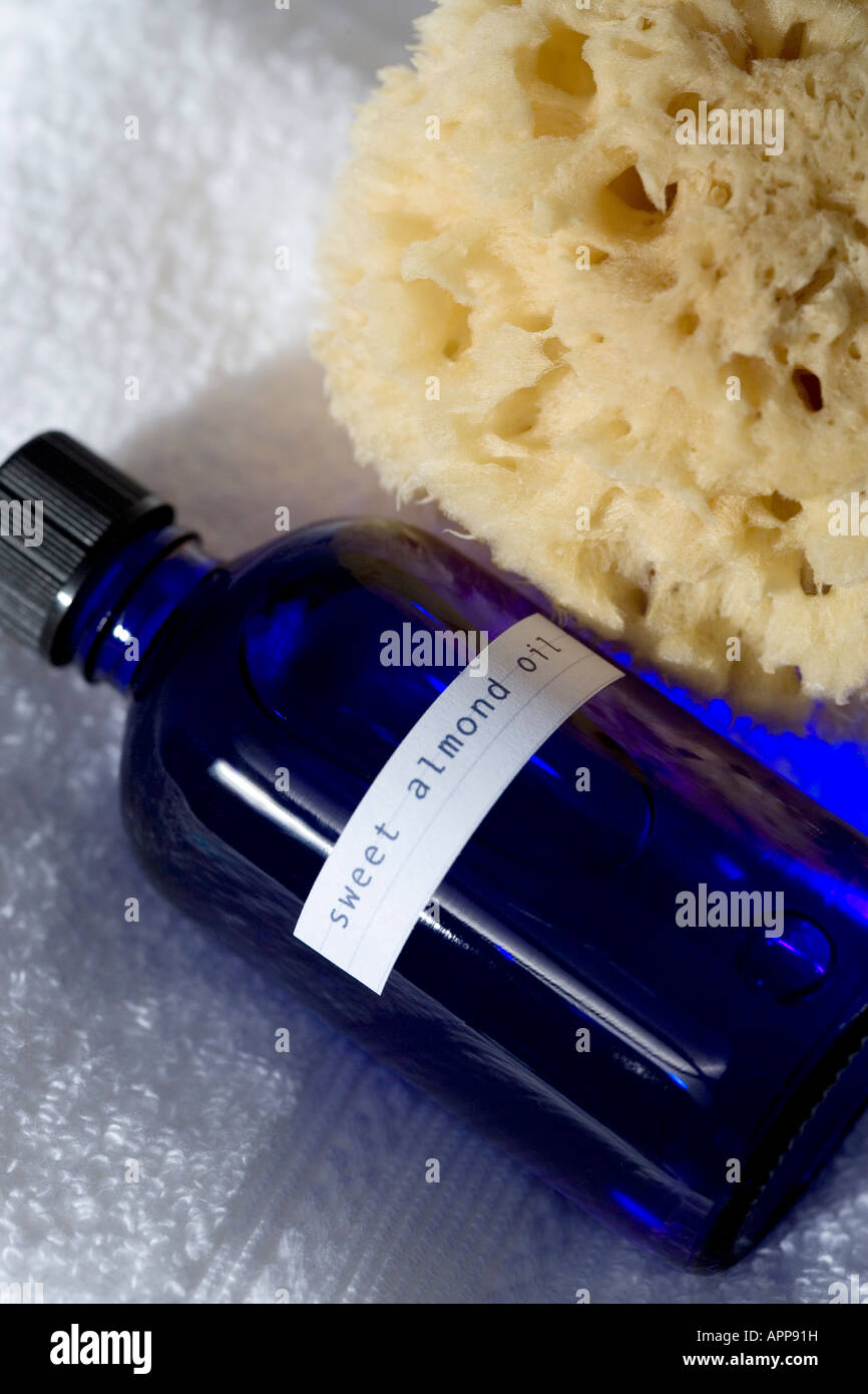 Aromaterapia: Mandorle dolci olio carrier sparato contro un asciugamano bianco con una spugna naturale Foto Stock