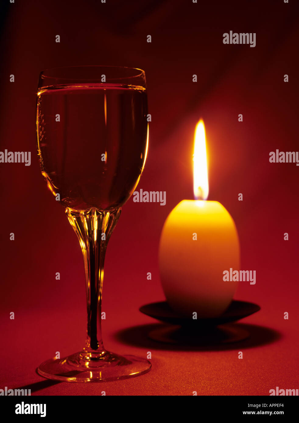 Sherry in un bicchiere accanto a candela incandescente su sfondo rosso Foto Stock