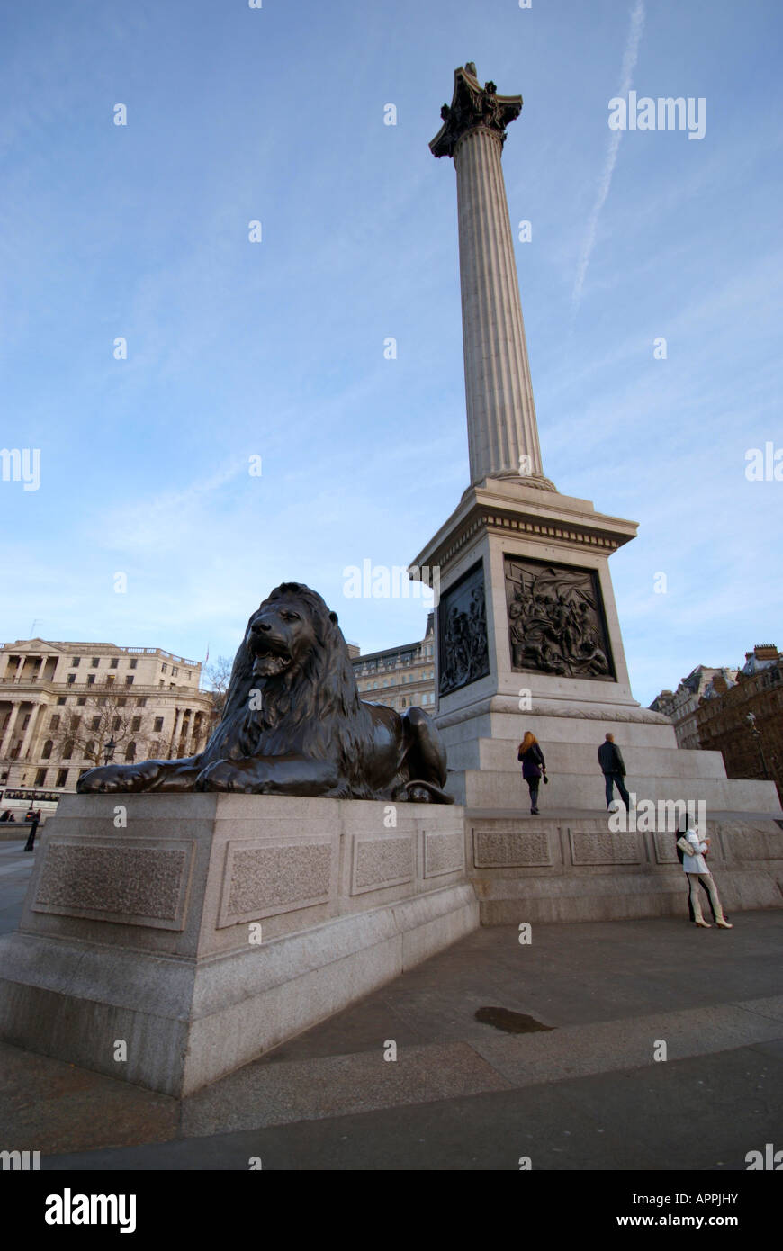 Mulino di turisti intorno alla base della colonna di Nelson accanto a un leone. Foto Stock