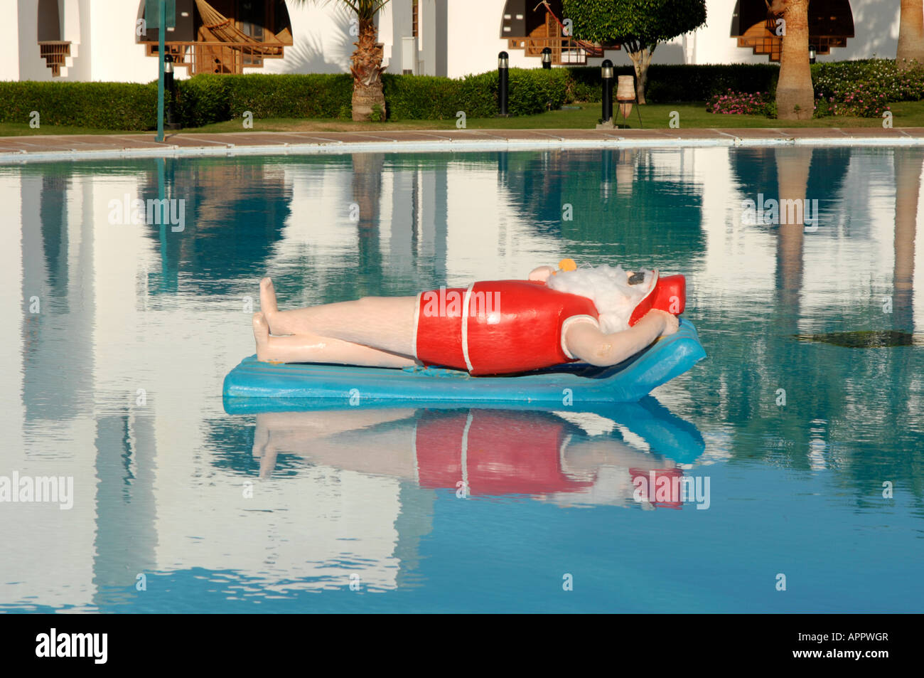 Babbo Natale sorseggiando un cocktail su un lilo in una piscina Foto Stock