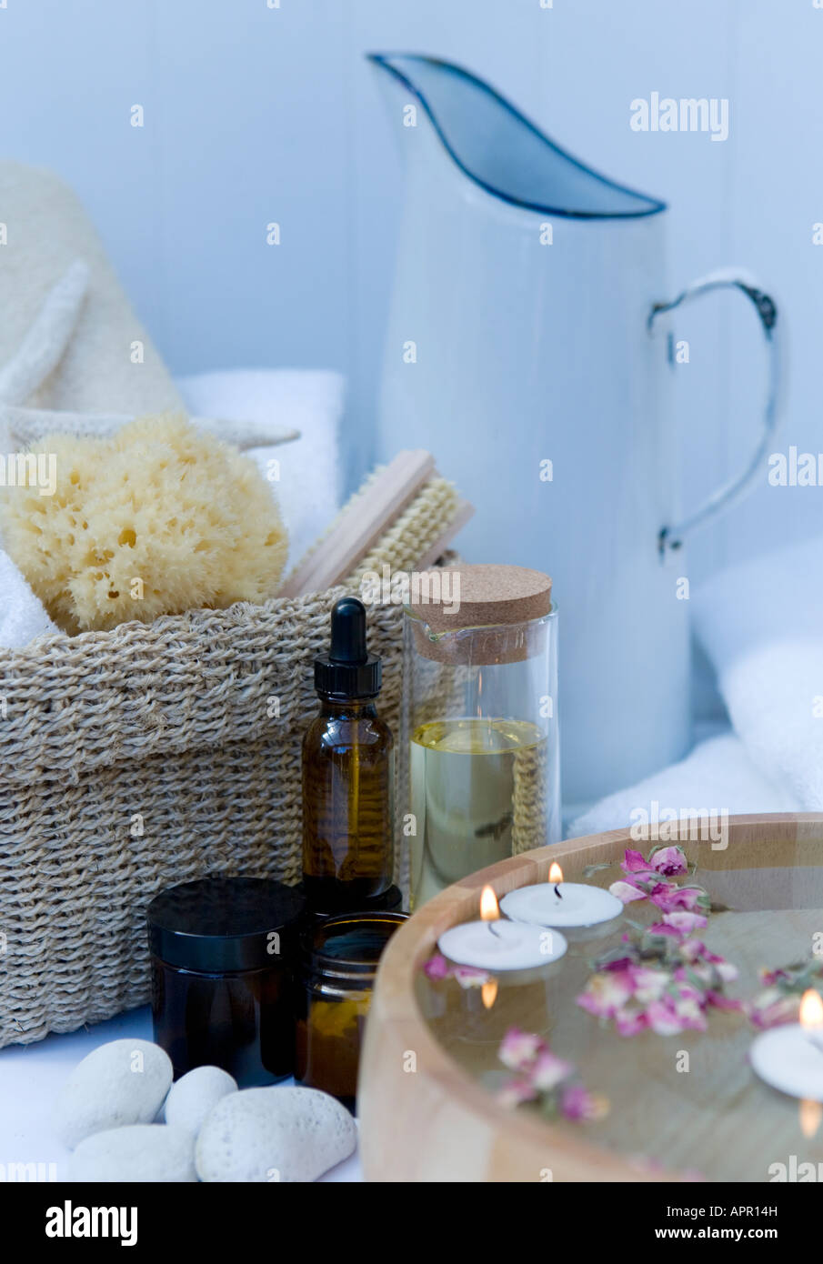 Bagno termale impostazione: gli olii aromatherapy vintage brocca di smalto, spugna naturale, ciotola di legno riempita con acqua e petali flottante Foto Stock