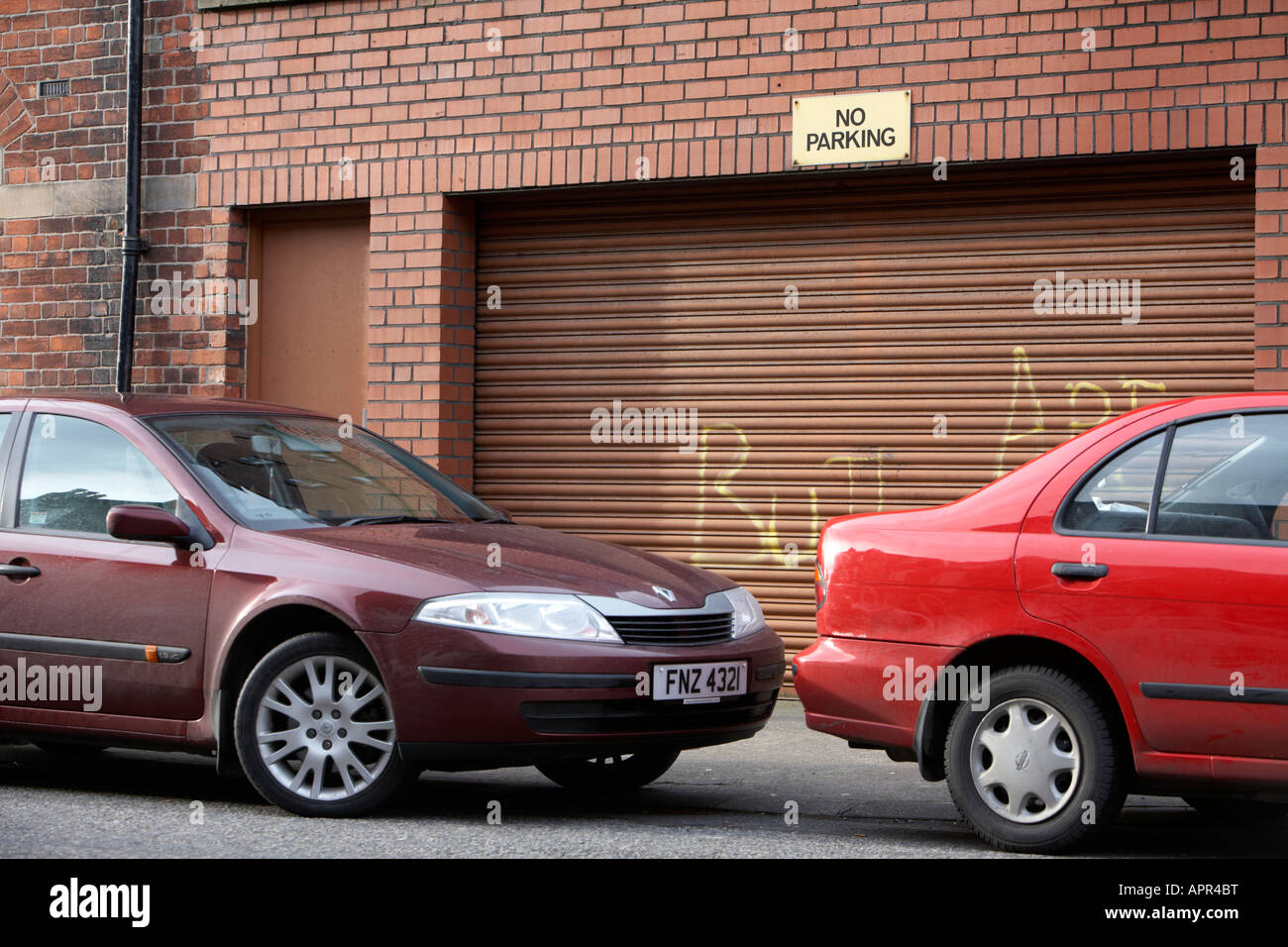 Due vetture parcheggiate nella parte anteriore del garage in acciaio otturatore con nessun segno di parcheggio Belfast Irlanda del Nord Regno Unito Foto Stock