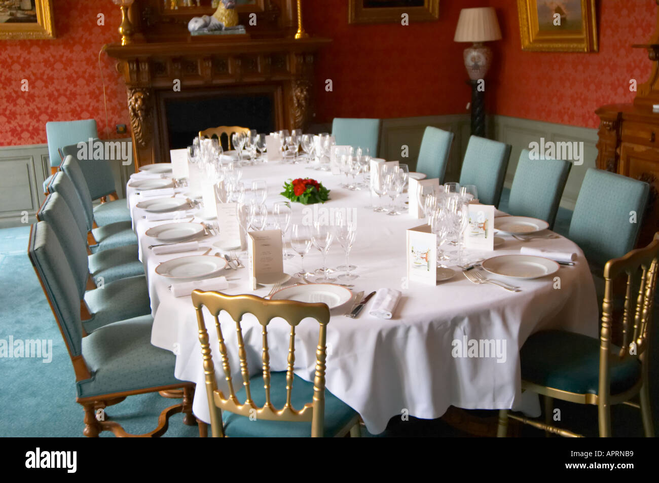 Il classico lussuosa sala da pranzo in stile antico impostato per una cena di gala con starched tovaglioli e tavolo bianco panno e molti bicchieri per la degustazione di champagne come visto attraverso la porta di ingresso le rose decorare la tavola e i menu a Champagne Deutz in Ay, Vallée de la Marne, Champagne, Marne, Ardenne, Francia, bassa luce grano sgranate Foto Stock