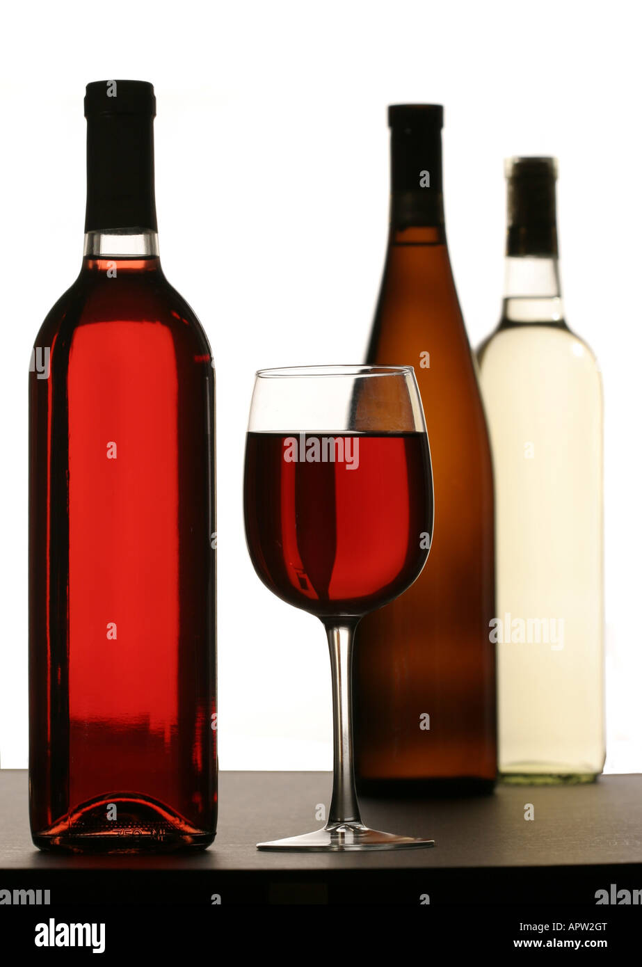 Di vetro riempita con il vino rosso con varietà di bottiglie di vino in background e foreground Foto Stock