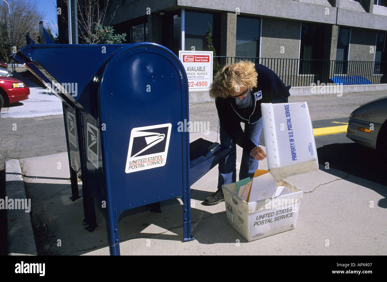 Un postino raccoglie la posta da un mail drop box Foto Stock