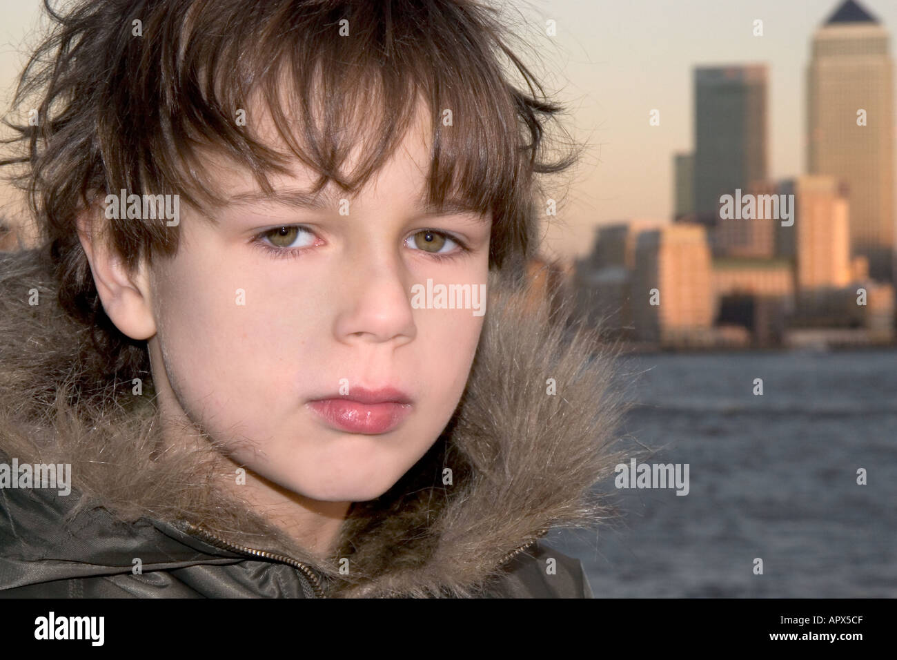 Ritratto di ragazzo che indossa un cappotto invernale con il cappuccio del fiume e gli edifici alti in background Modello rilasciato Foto Stock