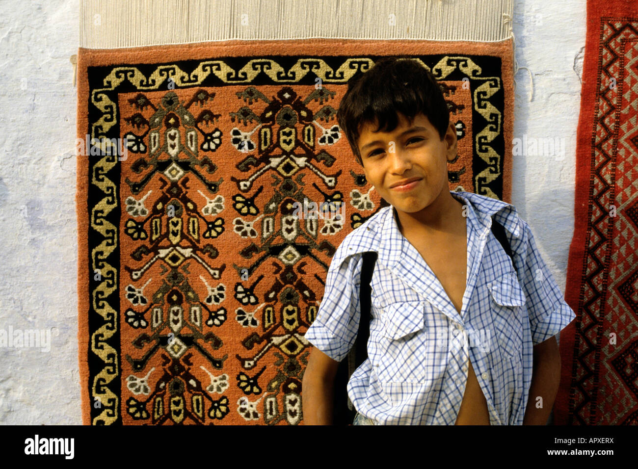 Giovani ragazzi tunisini in piedi contro tappeti tunisini appeso al muro  dietro di lui Foto stock - Alamy