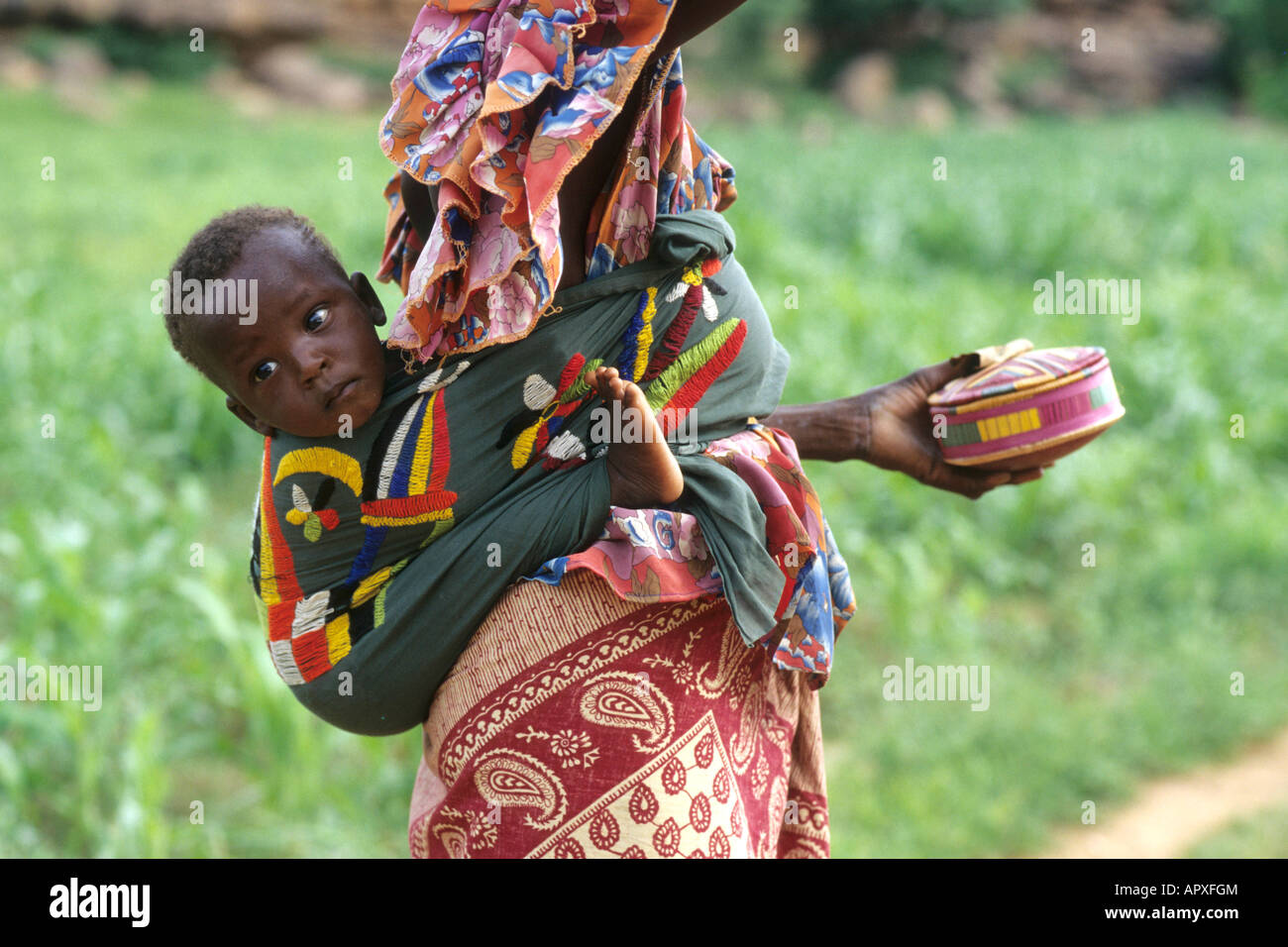 Giovane donna Peul indossando variopinti si avvolge con un bambino legato al suo indietro Foto Stock