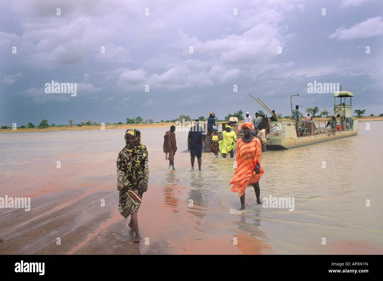 Traghetto sul fiume Niger con alcuni passeggeri a piedi a terra attraverso l'acqua poco profonda. Foto Stock