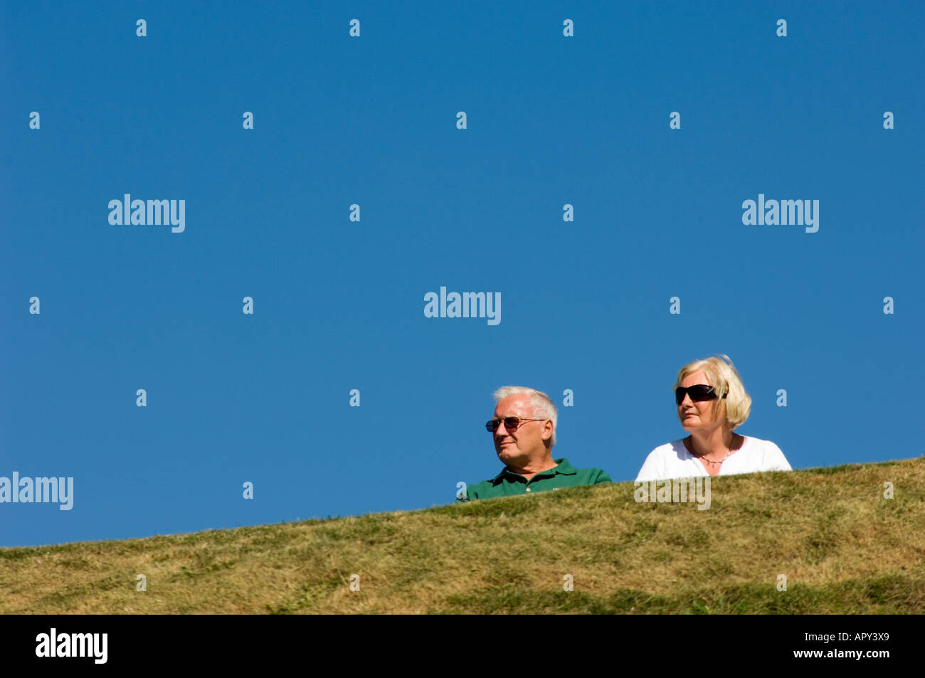 Un uomo e una donna, coppia di mezza età, contro il cielo blu, indossando occhiali da sole, pomeriggio estivo, Aberystwyth Wales UK Foto Stock