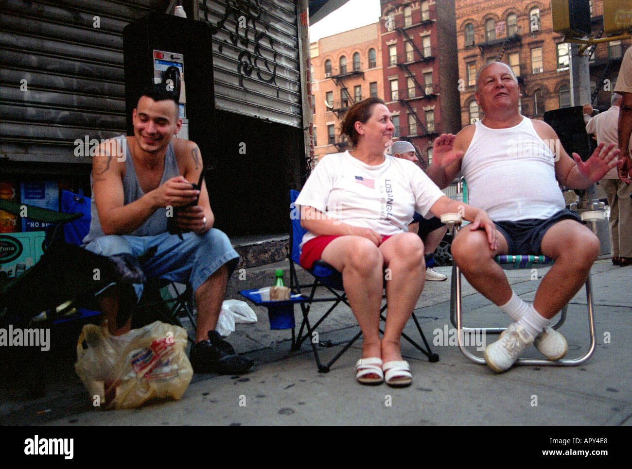 Gente seduta sul marciapiedi in calore estivo in alto a Manhattan New York City. Foto Stock