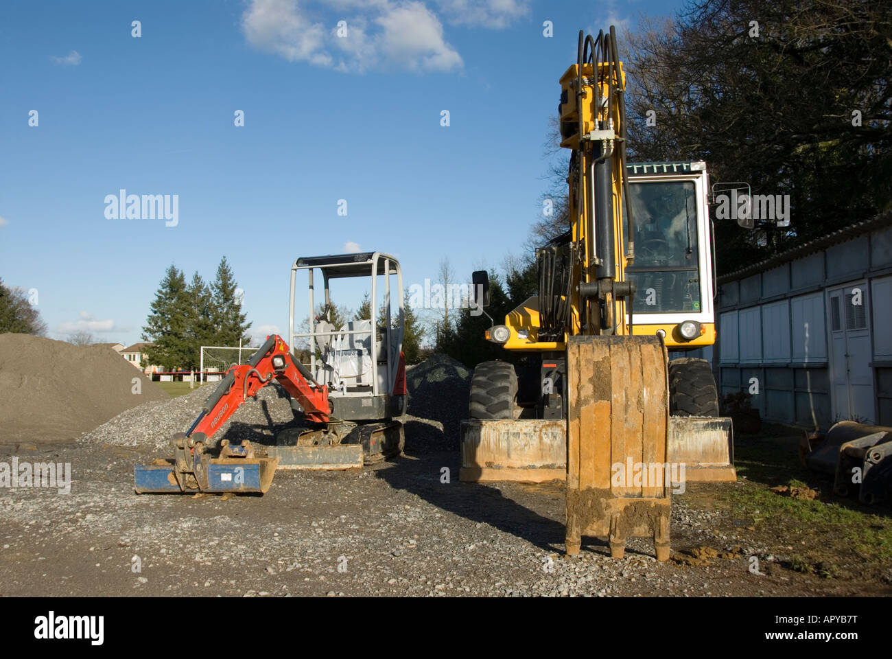 Immagine di un grandi costruttori digger parcheggiato a fianco di un mini escavatore Foto Stock