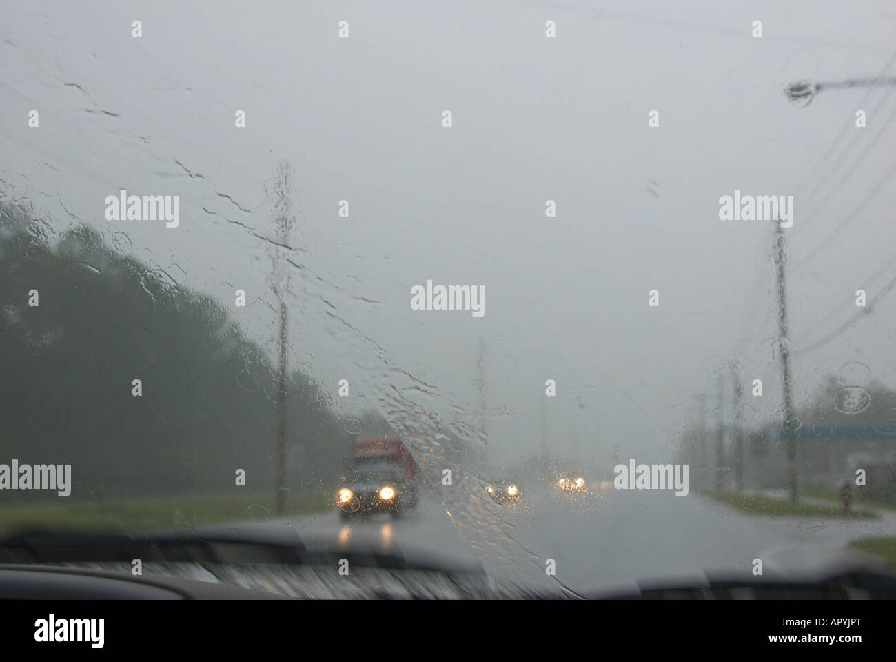 Auto auto parabrezza sfocato maltempo pioggia e spruzzo su autostrada pericolose condizioni di guida difensiva fari di guida Foto Stock