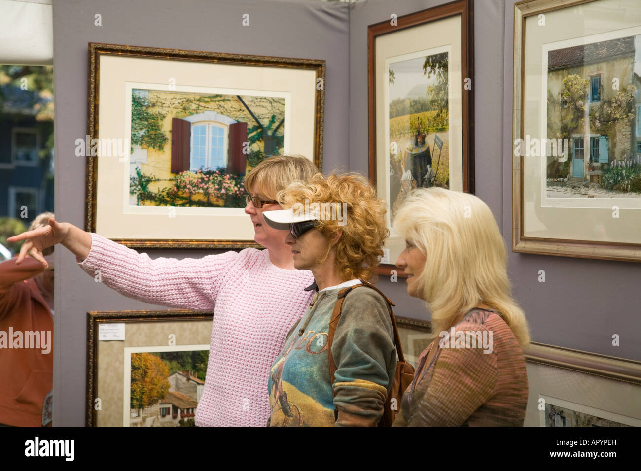 IOWA Est Davenport tre donne guardando arte esposte per la vendita in stand Riverssance Festival di Arte Foto Stock