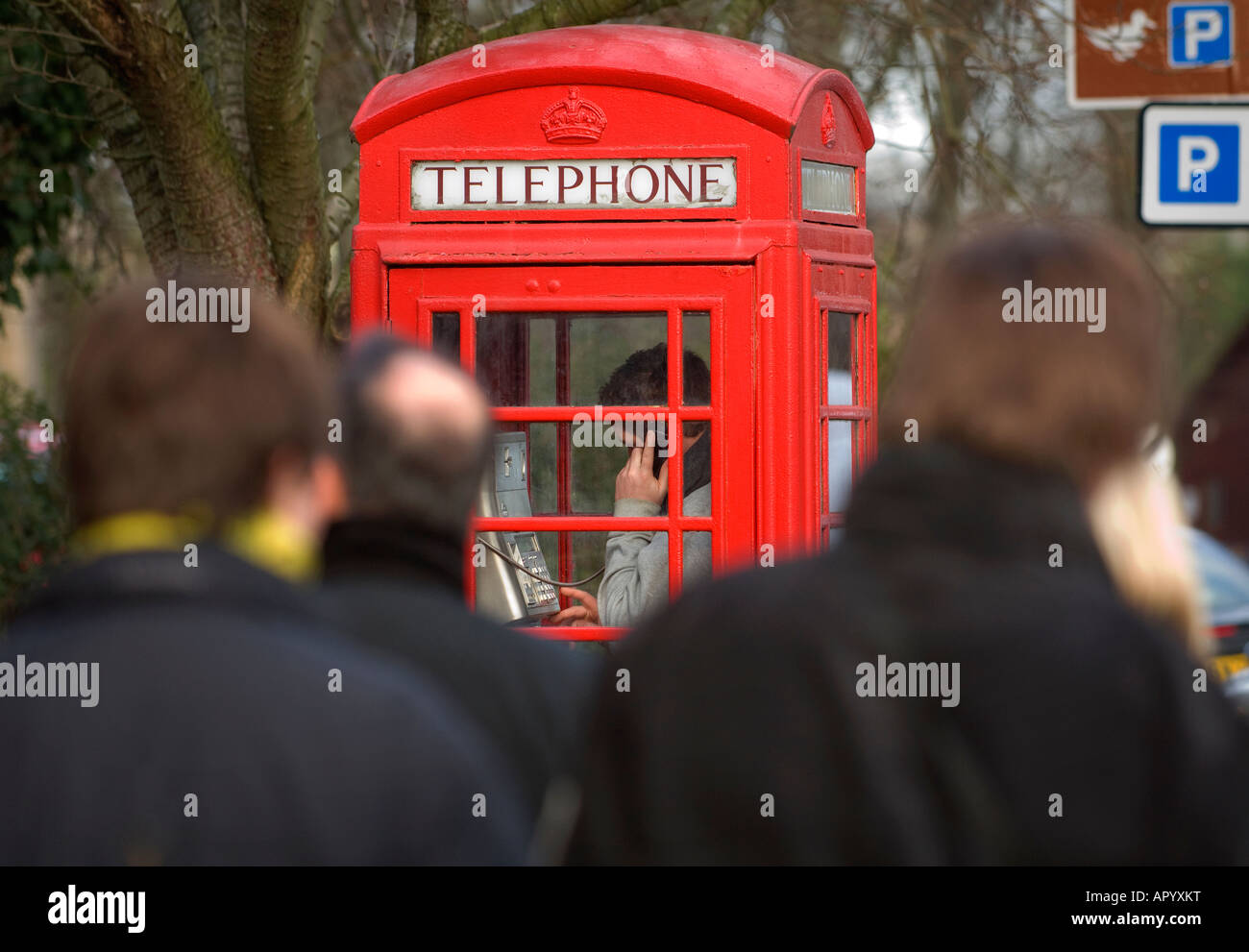 Un giovane uomo che utilizza un telefono rosso scatola in una strada urbana. Foto da Jim Holden. Foto Stock