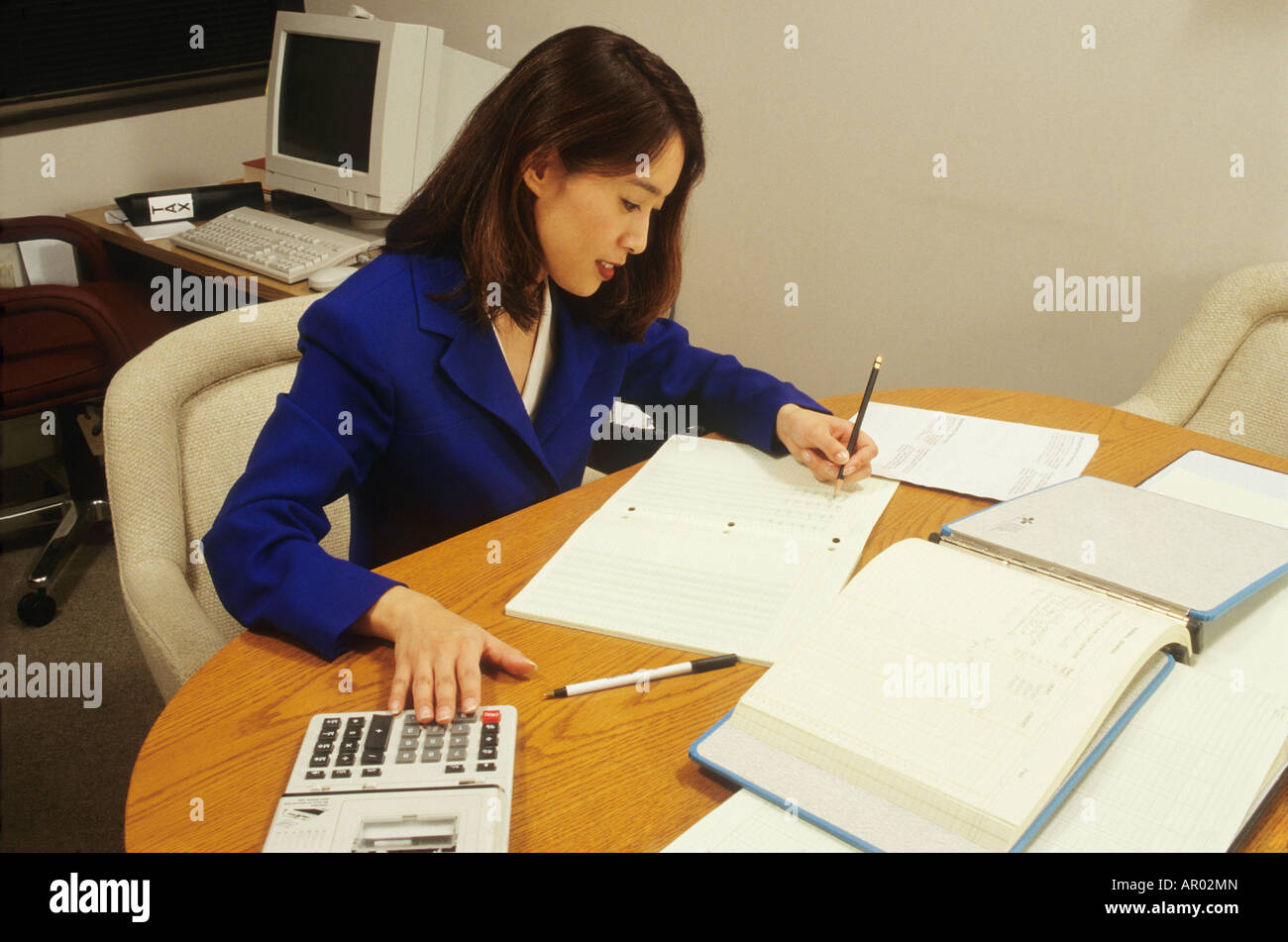 Ragioniere lavora in ufficio moduli fiscali calcolatrice carriera femminile Asiatico USA la matematica Foto Stock