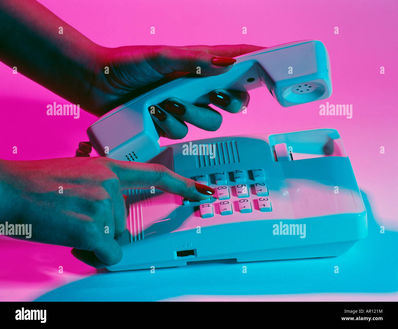 Una donna che tiene il ricevitore del telefono e compone il numero Foto Stock