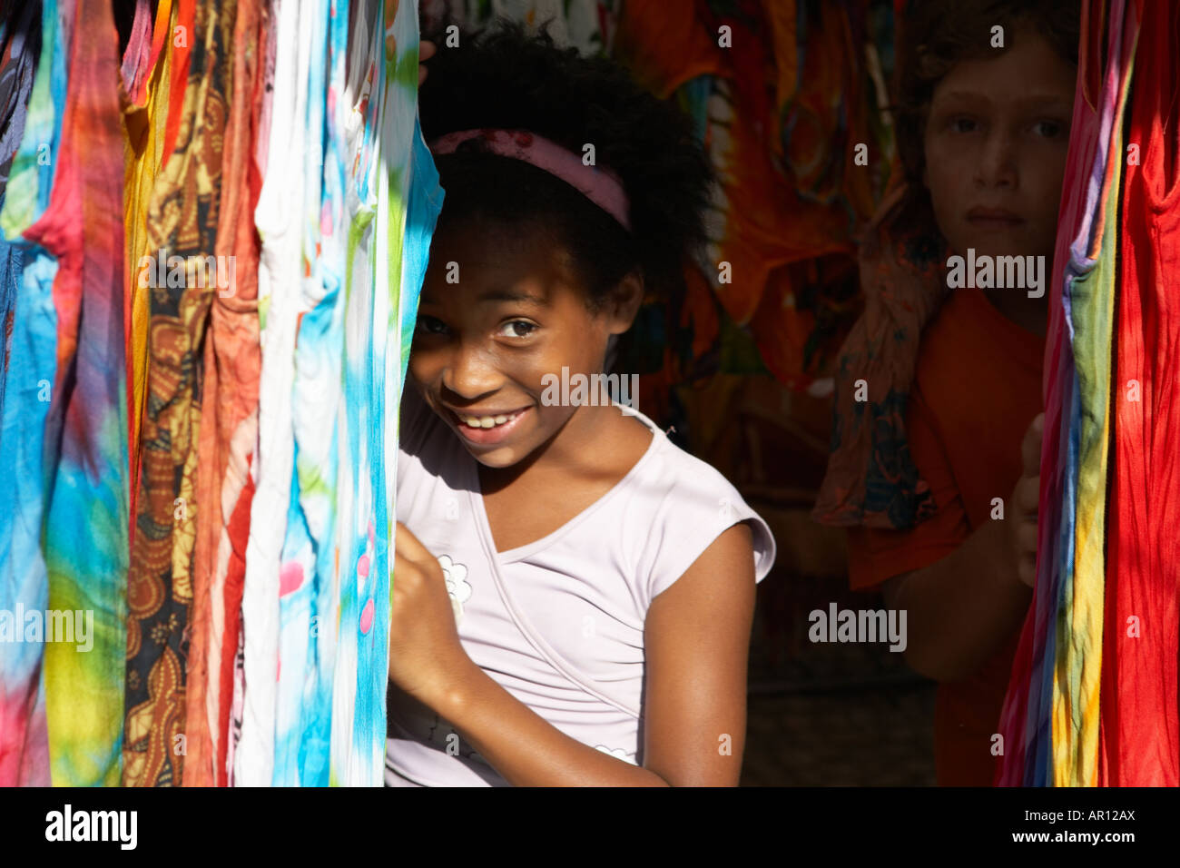 Ragazza sorridente da tra materiali in stallo fiera hippie Praca General Osorio a Rio de Janeiro in Brasile Foto Stock